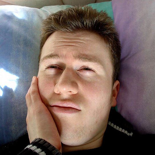 man holding chin with toothache